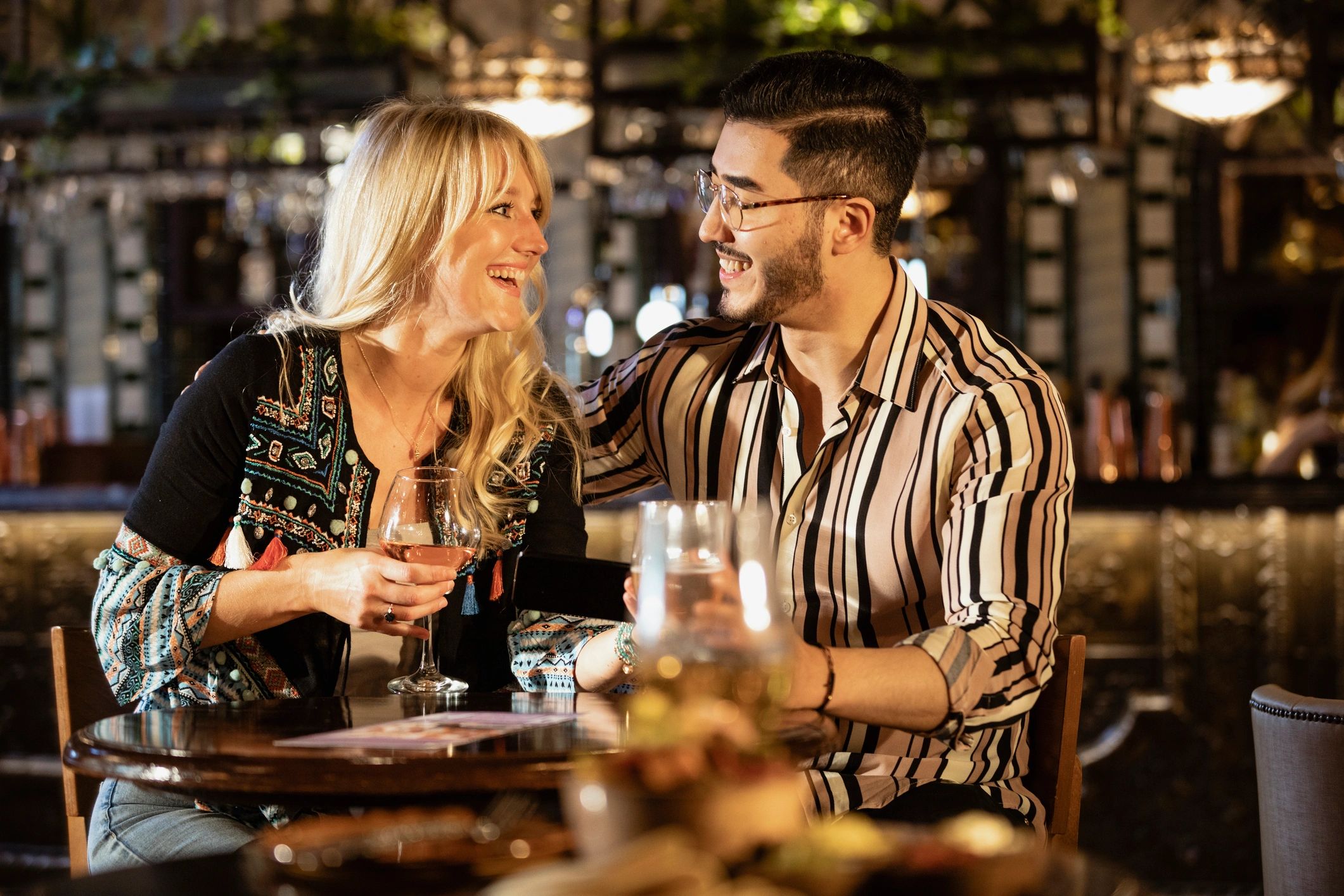 Two people enjoying wine together at a bar